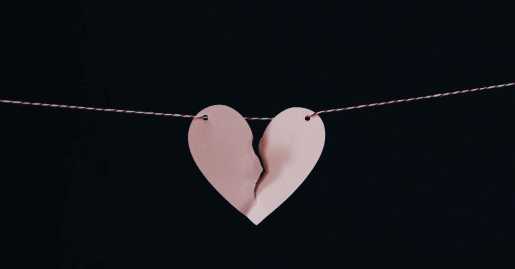 papercraft of a broken heart, ripped in two pieces hanging on a string