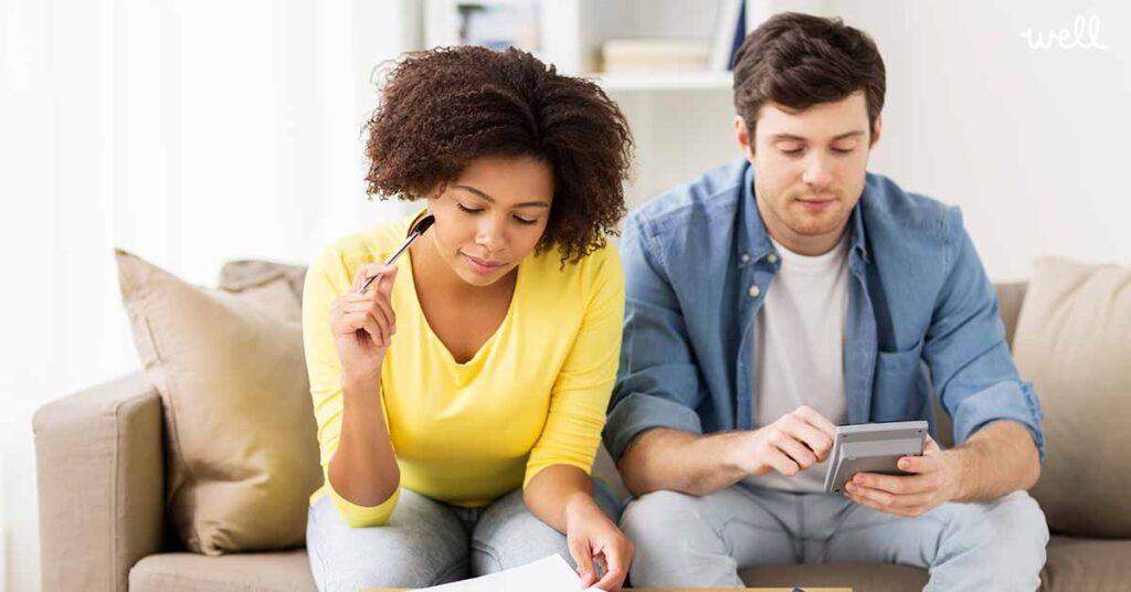 Man and woman sitting on a couch with a calculator and papers in front of them
