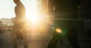 Business people in suits walking around in the early morning sun