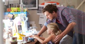 Picture of a man with a daughter at a laptop teaching how to type