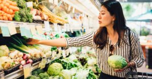Female holding a lettuce and browsing fresh vegetables