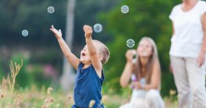 Happy child with family playing with five bubbles