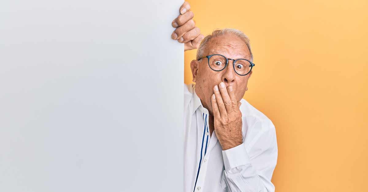 Old man with his hand in front of his mouth with a surprised expression