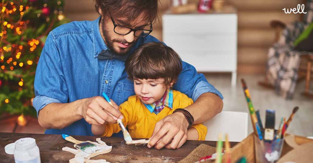 Father and son painting wooden figurines at christmas time