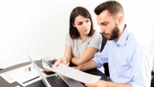 Couple looking at a laptop with paperwork in front of them