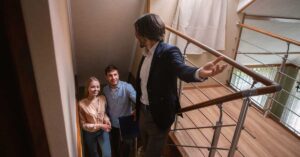 Real estate agent showing a young married couple entrance to upstairs of a house