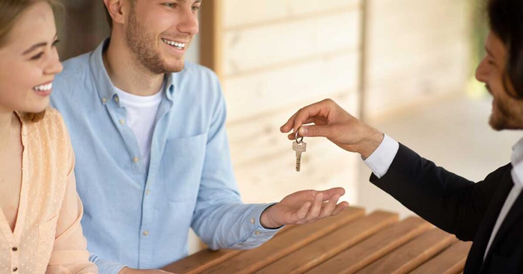 Real estate agent handing over keys to a young couple