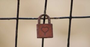 Close up view of a rusty lock with a heart engraved into the front