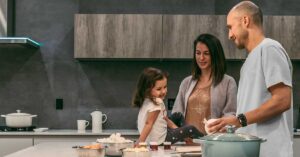 Family cooking in a kitchen with child sitting on the tabletop