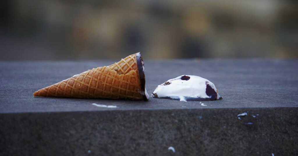 a close up of a ice cream cone with a spilt ice cream