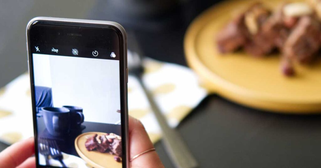 Person taking a photo of a meal on a wooden plate