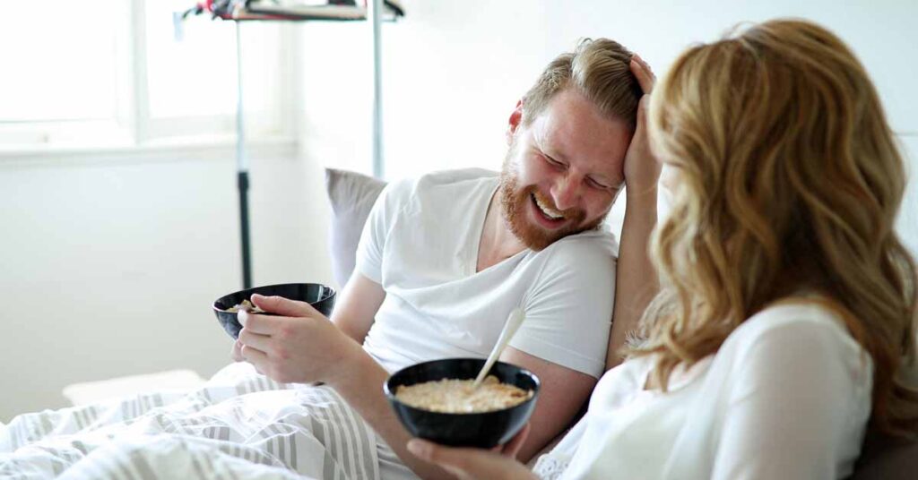 Young attractive couple having breakfast in bed.